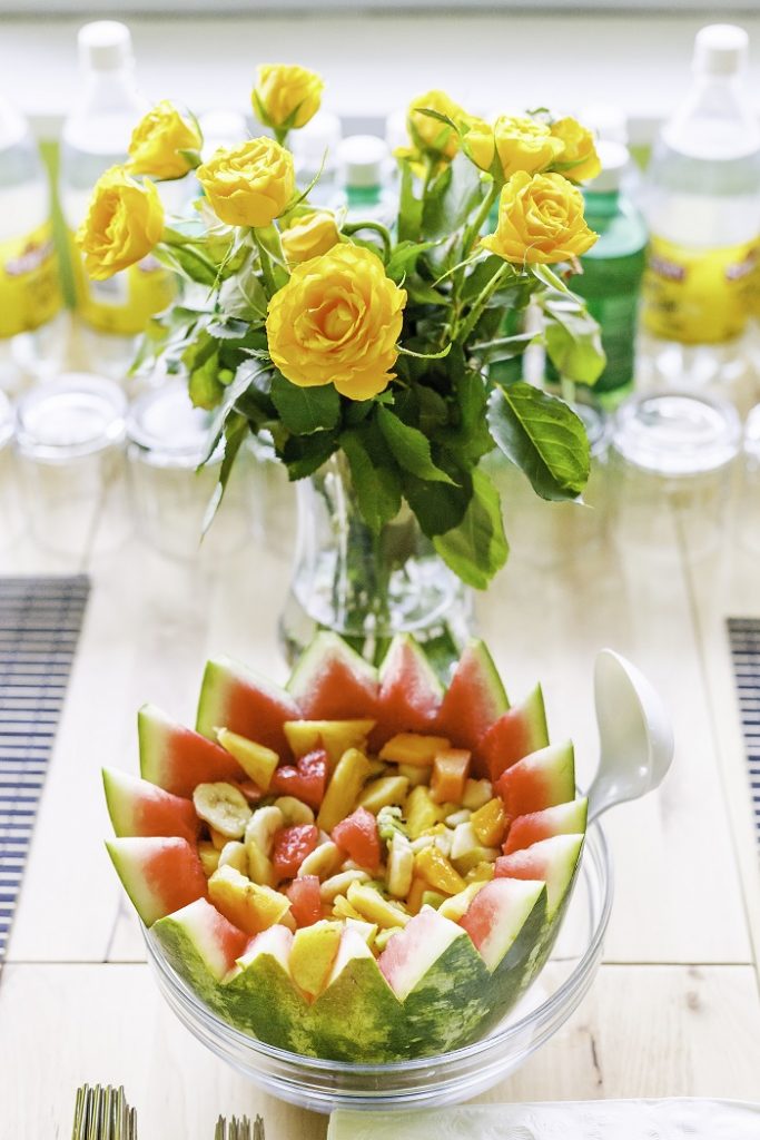 A fruit salad mixed in an artistically-cut watermelon half.